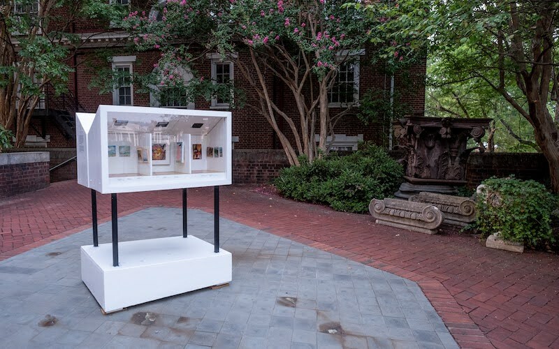 LMA is shown in the courtyard. It is white, angular, modern, and it is secured to a white base with four skinny black legs.