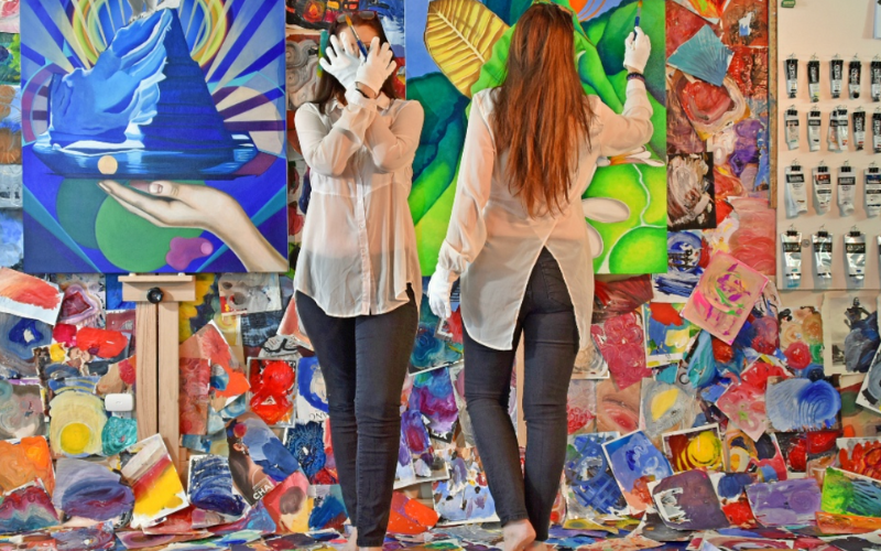a woman with long hair wearing a white blouse and blue jeans standing in front of and on top various colorful abstract art prints. She's crossing her hands in front of her face and is wearing white gloves. The woman is pictured again superimposed on the same background now facing one of two large canvases on the wall.